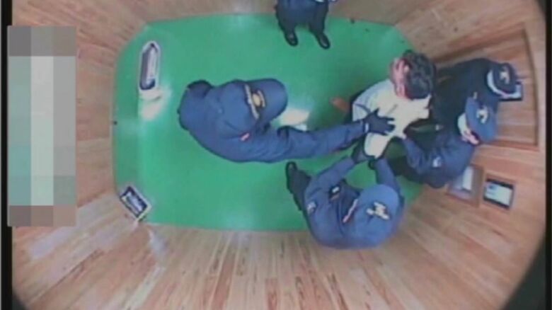 職員に囲まれるフジイさん（弁護団提供）