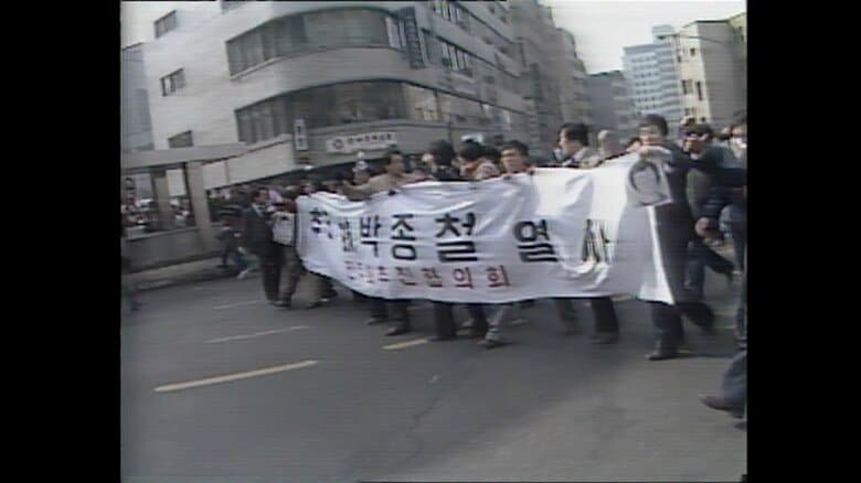 横断幕や朴鐘哲さんの遺影を掲げ行進するデモ隊（1987年）