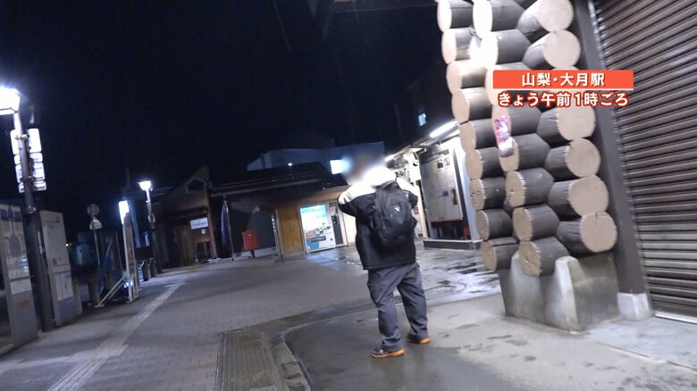 シャッターが閉まった駅の前でぼう然とたたずむ男性