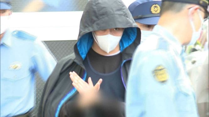 殺人容疑の送検時、カメラに手でバツを作った佐藤容疑者
