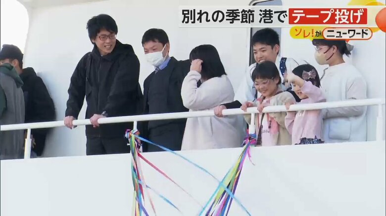 別れの紙テープを持ち、手を振る乗客の姿