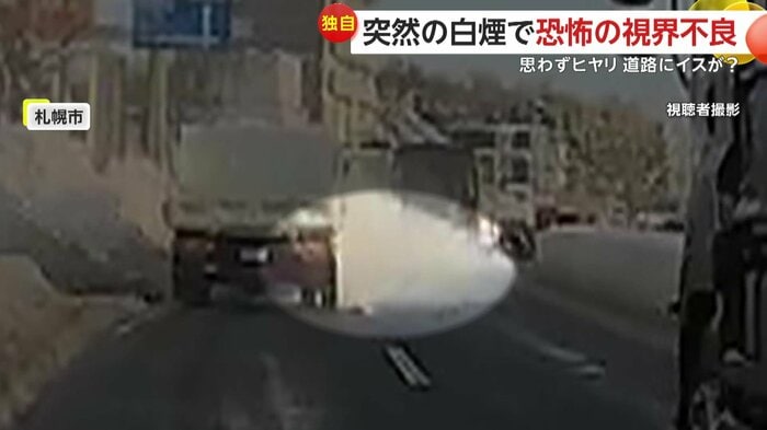 トラックの車体の下から白煙？