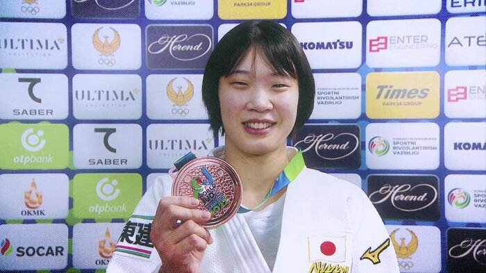 銅メダルを持つ新添