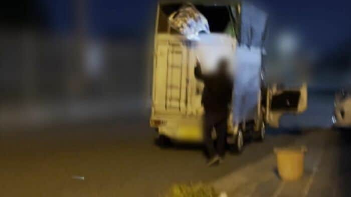 アルミ缶の入った袋を荷台に投げ入れる男性