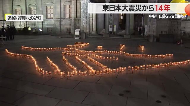 ロウソクでかたどられた“復興を願って手と手をつなぐハンドシェイク”の形と「3.11」の文字