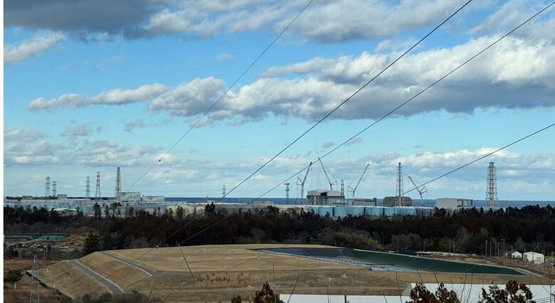 福島県大熊町の見晴台から見た福島第一原発（1～6号機）　作業用のクレーンが立ち並ぶ　手前の“盛り土”は除染に伴い発生した土壌を保管する「中間貯蔵施設」（筆者撮影）