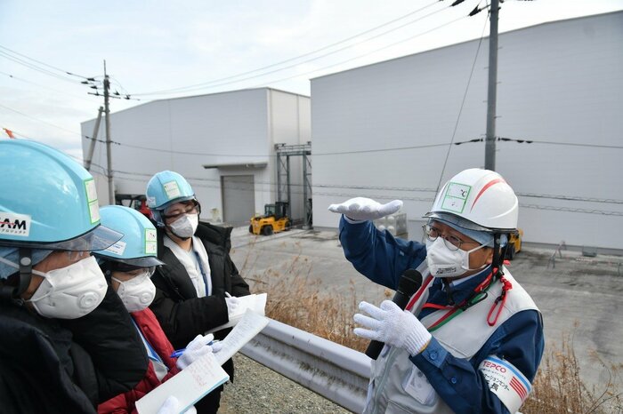 固体廃棄物貯蔵庫前で説明する木元さん　 現在、がれきなどを一時保管するための第11棟を建設中だ（代表撮影）