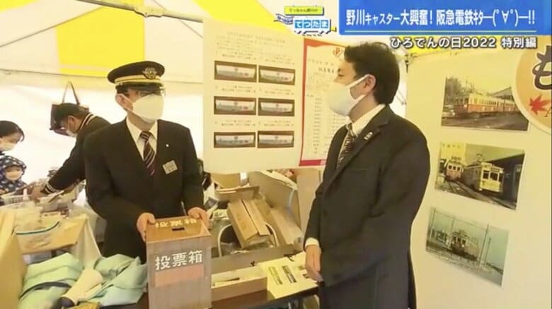 阪急電車館・館長（左）とグッズ話で盛り上がる野川アナ