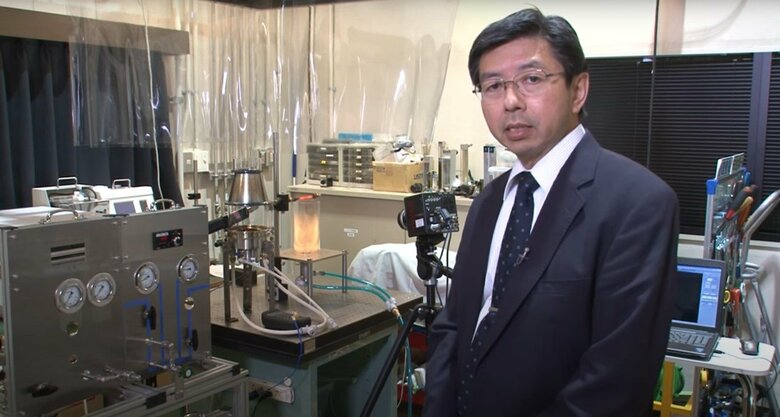 実験装置を前に説明する小林教授　写真：科学技術振興機構