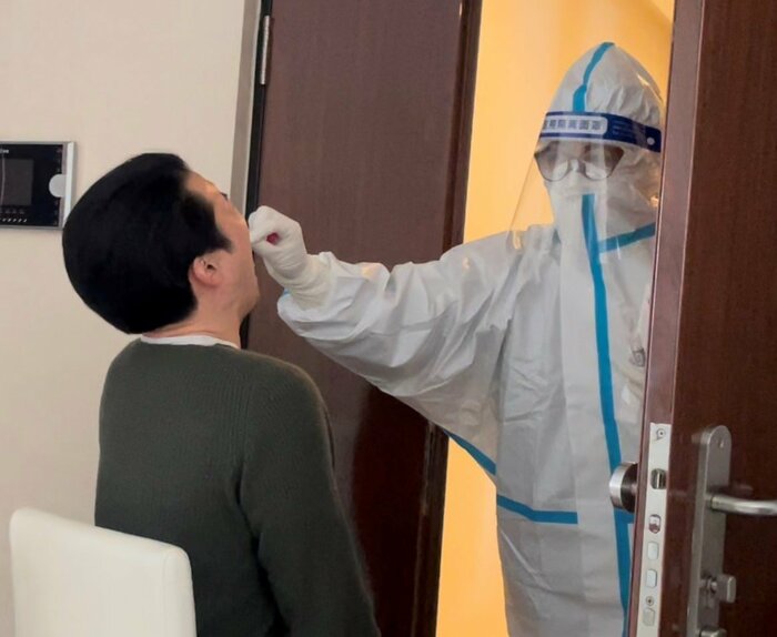 隔離中の北京市の自宅で行うPCR検査 検査員が防護服を着てやって来る