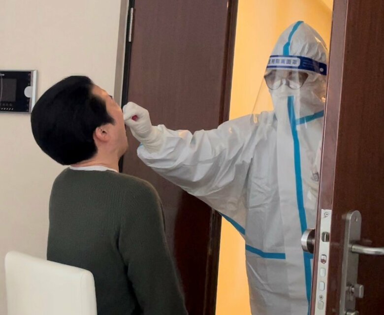 隔離中の北京市の自宅で行うPCR検査 検査員が防護服を着てやって来る