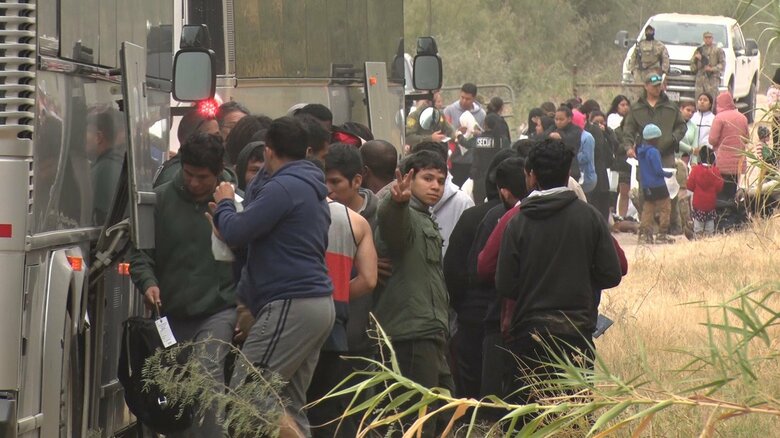 収容所に向かうバスに乗り込む不法入国者達
