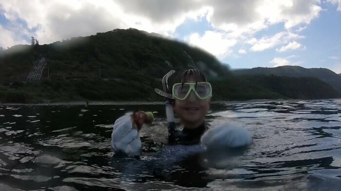 海に潜りペットボトルのごみを拾う生徒