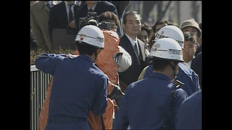 オレンジ色の防護衣を装着する武田さんの姿がフジテレビの映像アーカイブに残されていた（場所は霞ケ関駅）