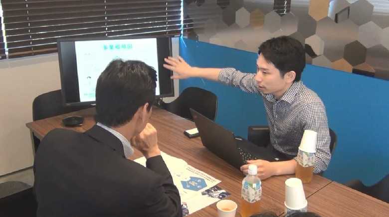 話を聞く西村官房副長官(左)と事業内容を説明する「キャディ」の加藤代表(右)
