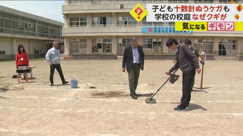 教師たちが金属探知機で校庭を調査している