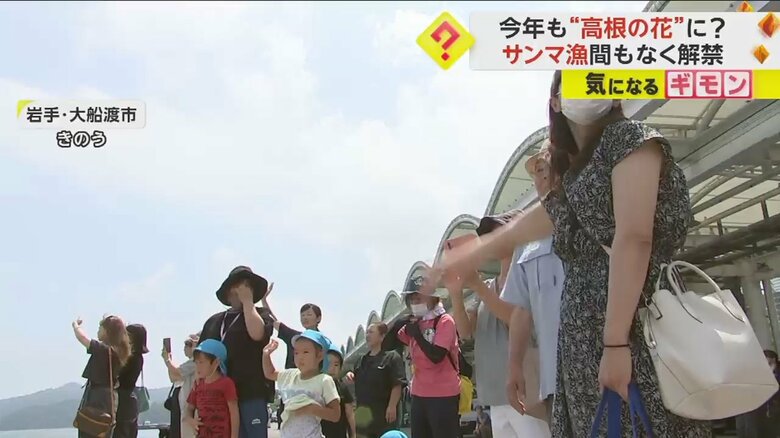 漁船に大きく手を振って見送る、漁師の家族たち