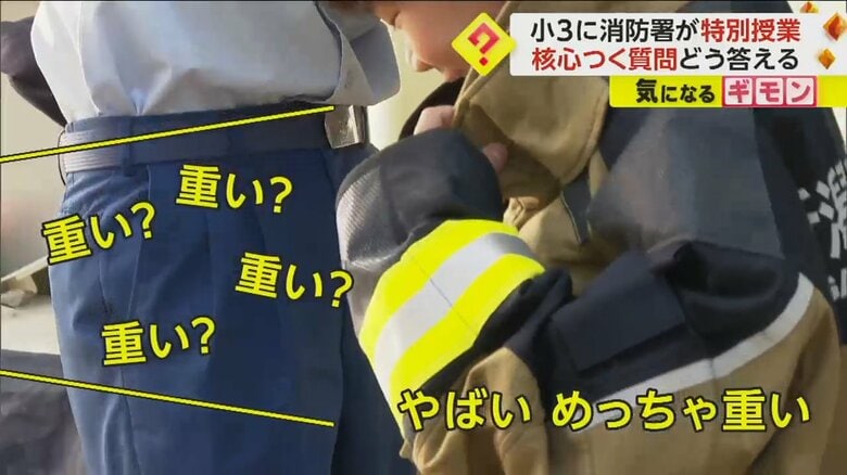 「やばい、めっちゃ重い」と答える防火服を着た小学生