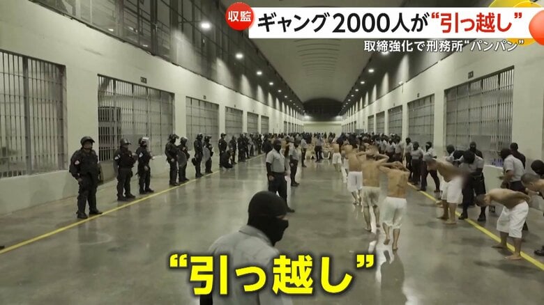 上半身裸で走る男らが、姿勢を低くして刑務所に入っている様子