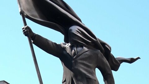 バンクシーの新作ロンドンに現る　旗で顔が隠れたスーツ姿の男性「彫像」　台座にバンクシーの署名　自身のSNSで公表
