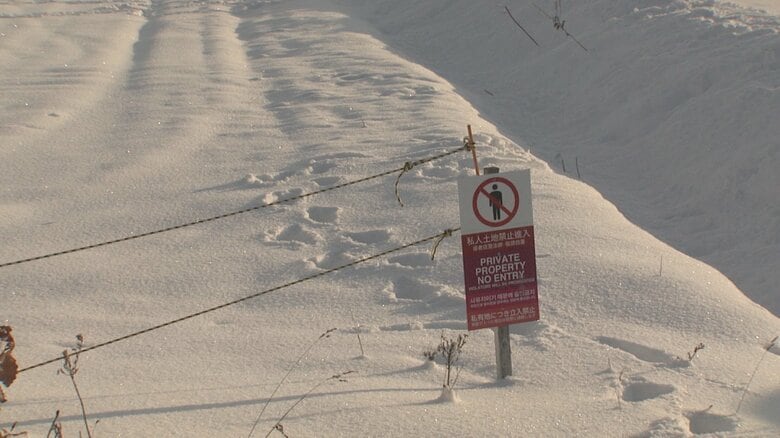 立ち入り禁止と書かれた看板横から畑に侵入している足跡