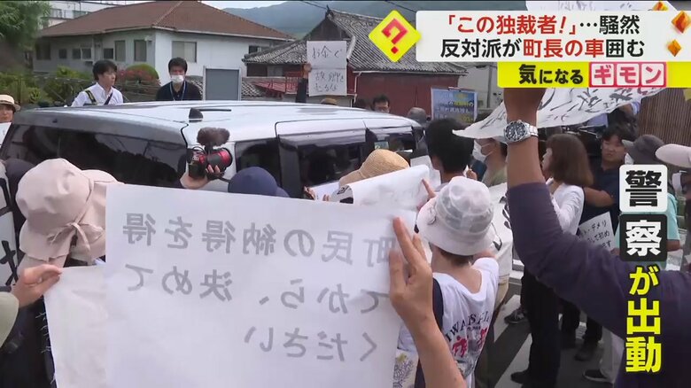 「お金で故郷を売るな」と書かれた紙を住民が掲げている