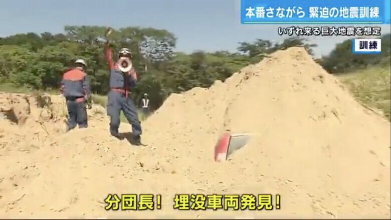 土砂に埋まった車を発見したと報告する隊員