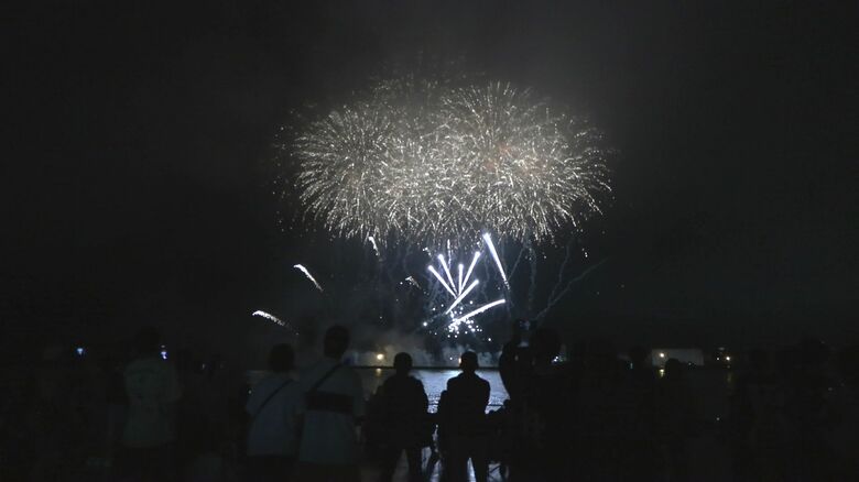 海上に打ちあがる花火を楽しむ観客
