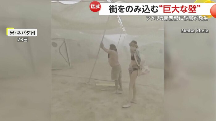 テントのポールを支える人