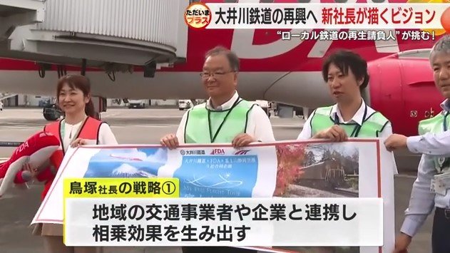 航空会社スタッフらとツアー資料を掲げる鳥塚社長