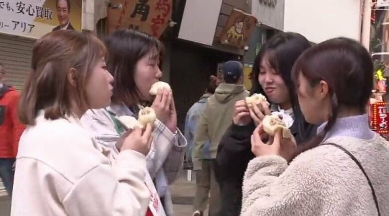 豚まんを本店のある戎橋筋商店街で頬張る客