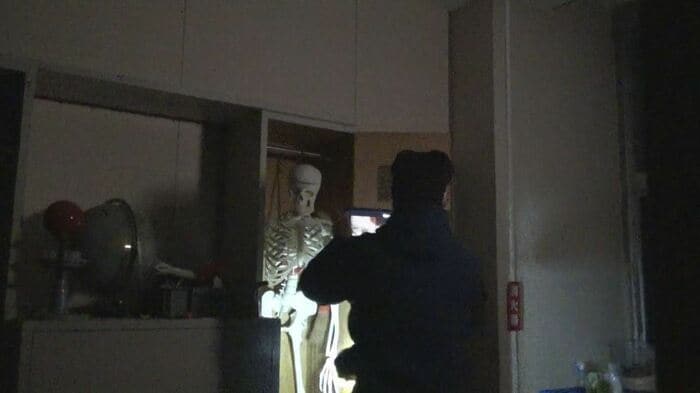 懐中電灯とタブレットを手に夜の学校を探検する教師