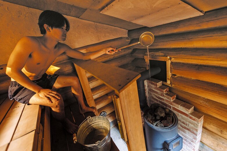 柄杓に汲んだ水を、ストーブの上に載せた石に静かに注ぐと、熱せられた蒸気が小屋の中に立ち込める（『小屋を建てる』より）