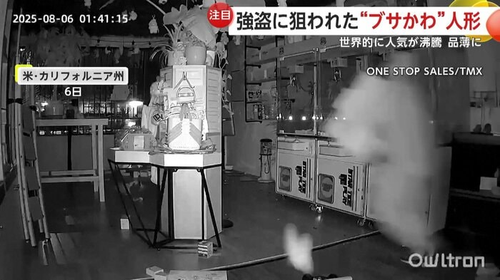 大きな箱を抱えて店の外へと運び出す強盗
