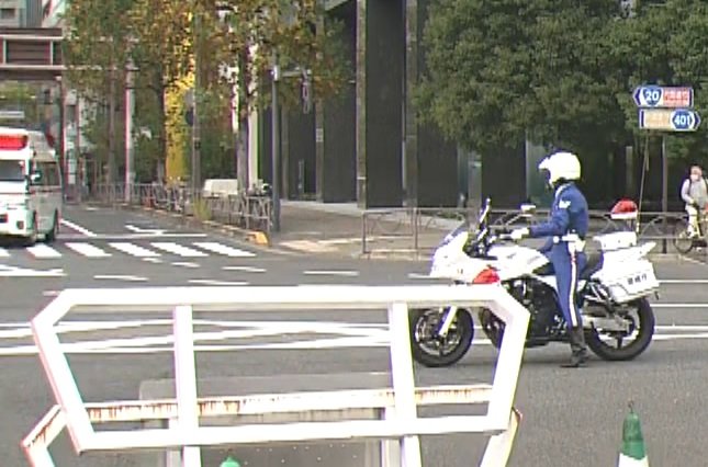 警察官の誘導で先に交差点を右折していく救急車(28日)