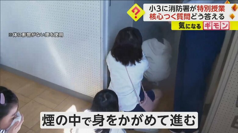 煙の中を身をかがめて進む小学生
