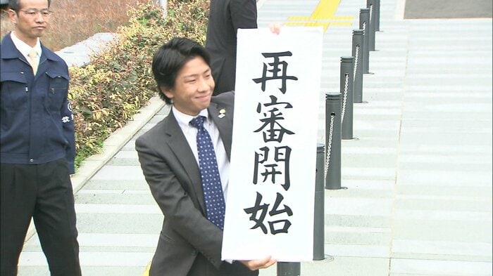 「再審開始」と掲げる弁護人(2014年)