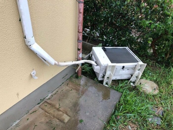 強風で室外機は横倒しになっている。