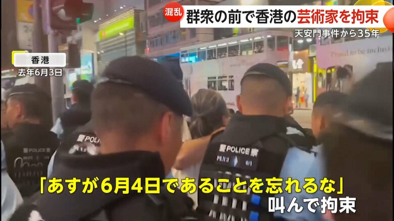 複数の警察官に取り囲まれて拘束される芸術家の男性