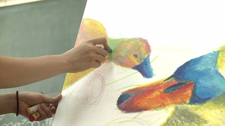 高橋さんはクレヨンを塗り重ねて作品を描いていく