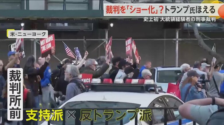 プラカードを掲げ、列になって歩く反トランプ派の人々