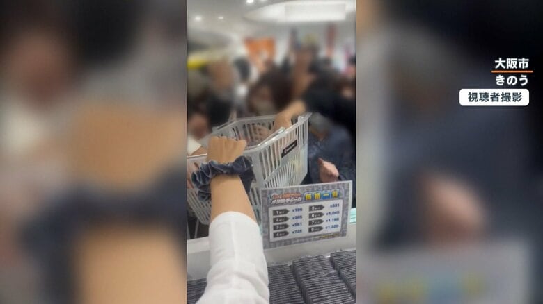 かごに入れられた商品に押し寄せる人々