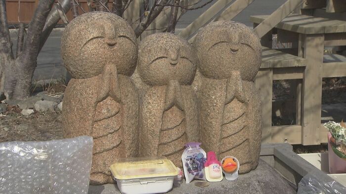 遊具で遊ぶ子供たちを見守る3体の地蔵