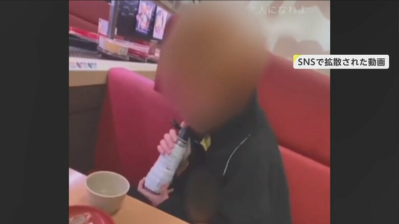 少年がしょう油ボトルの注ぎ口をなめる様子