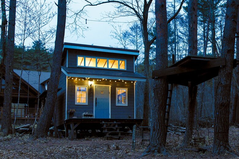 カラマツの森に立つ小屋。木々の間には小屋に先立って作ったツリーデッキがある。電気は母屋から引いている（写真：高橋郁子）