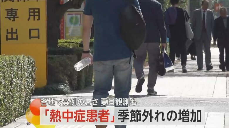 半袖姿にペットボトルを持ち、街を歩く人の姿