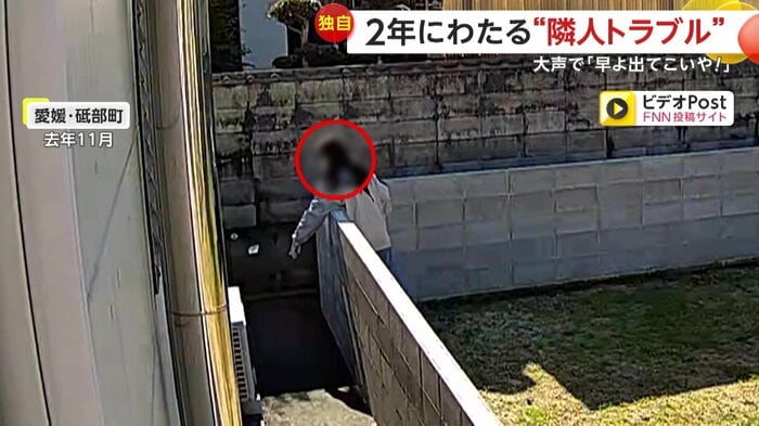 何かを隣家に投げつける女性