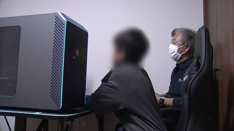 施設スタッフと一緒にパソコンに向かう子供