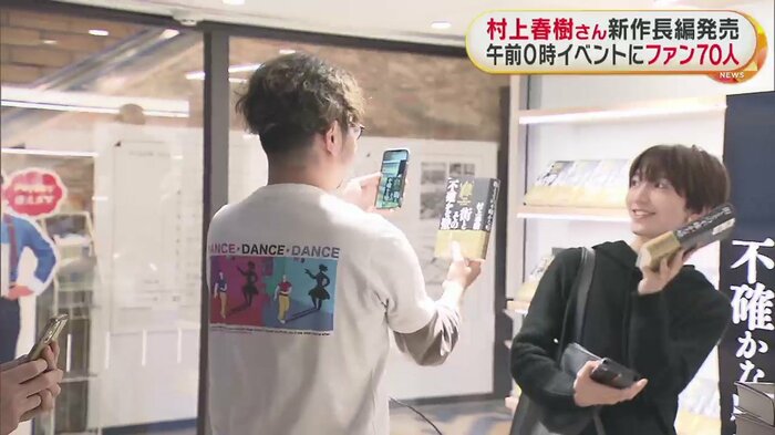 新作を購入し、記念撮影するファンたち