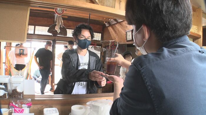 お客さんにコーヒーを手渡す大月さん